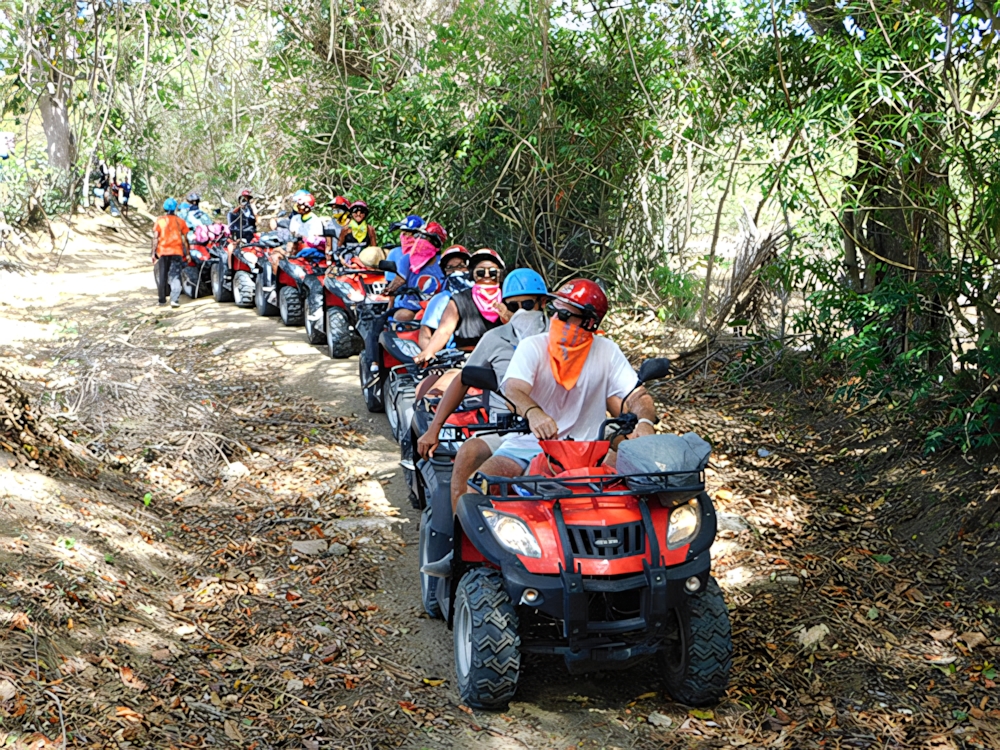 Rider on an ATV quad bike kicking up dust on a dirt trail
