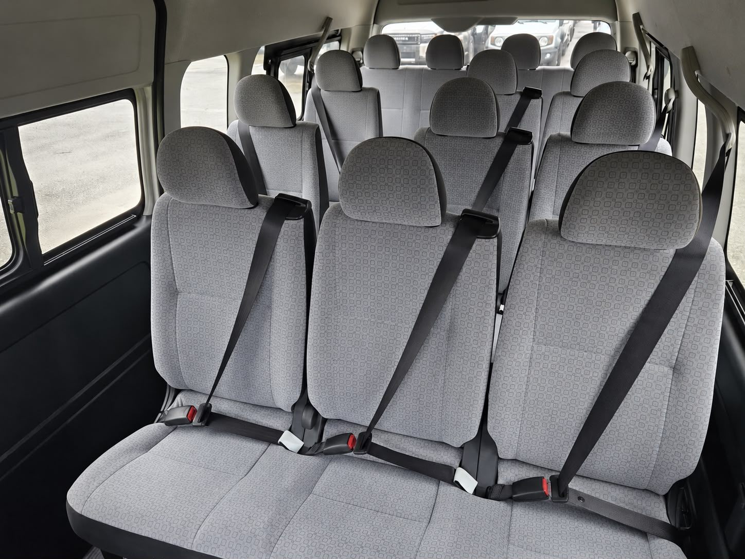 Grey fabric seats inside a Toyota Hiace van, seen from the back row