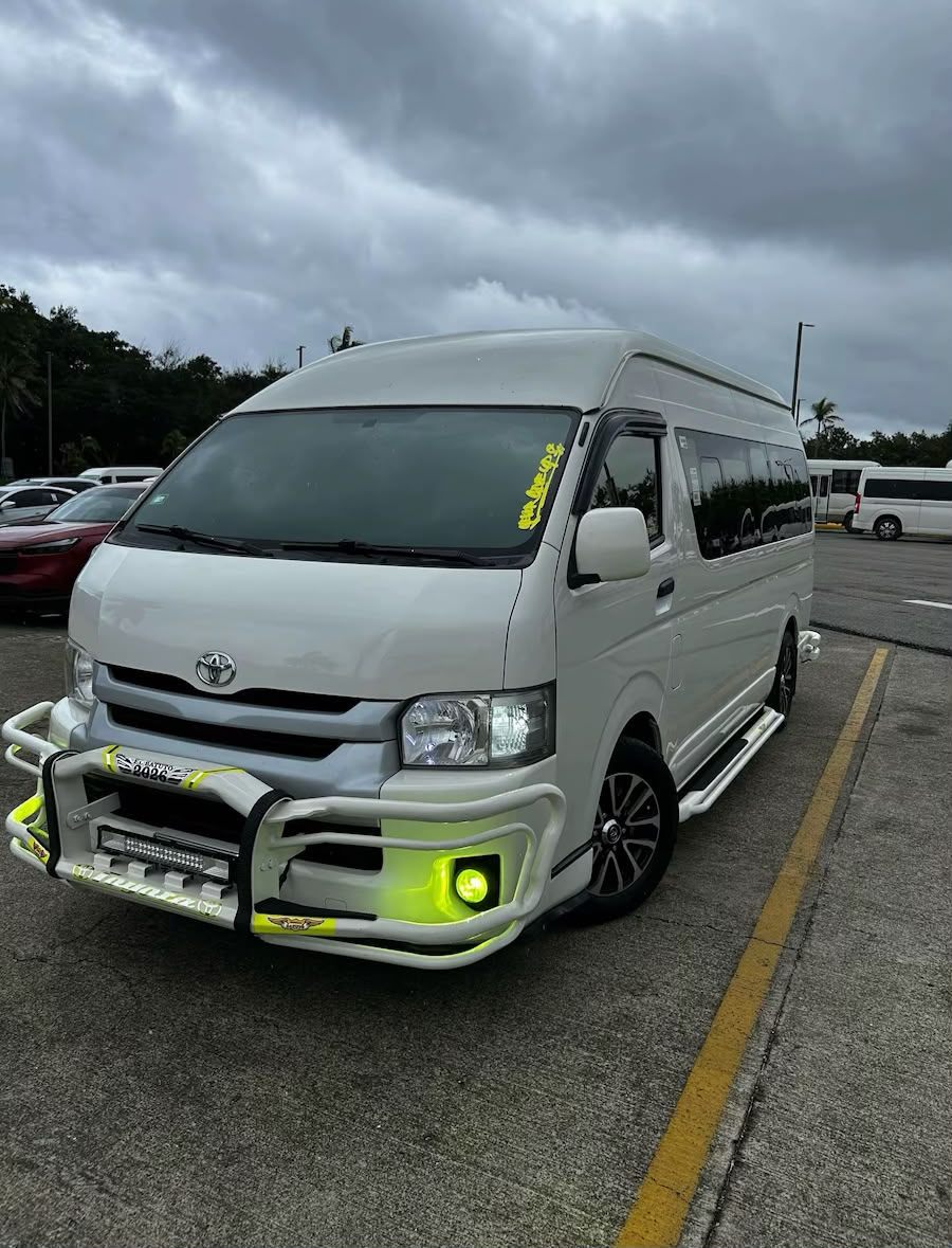 White Toyota Hiace van with off-road styling under a cloudy sky