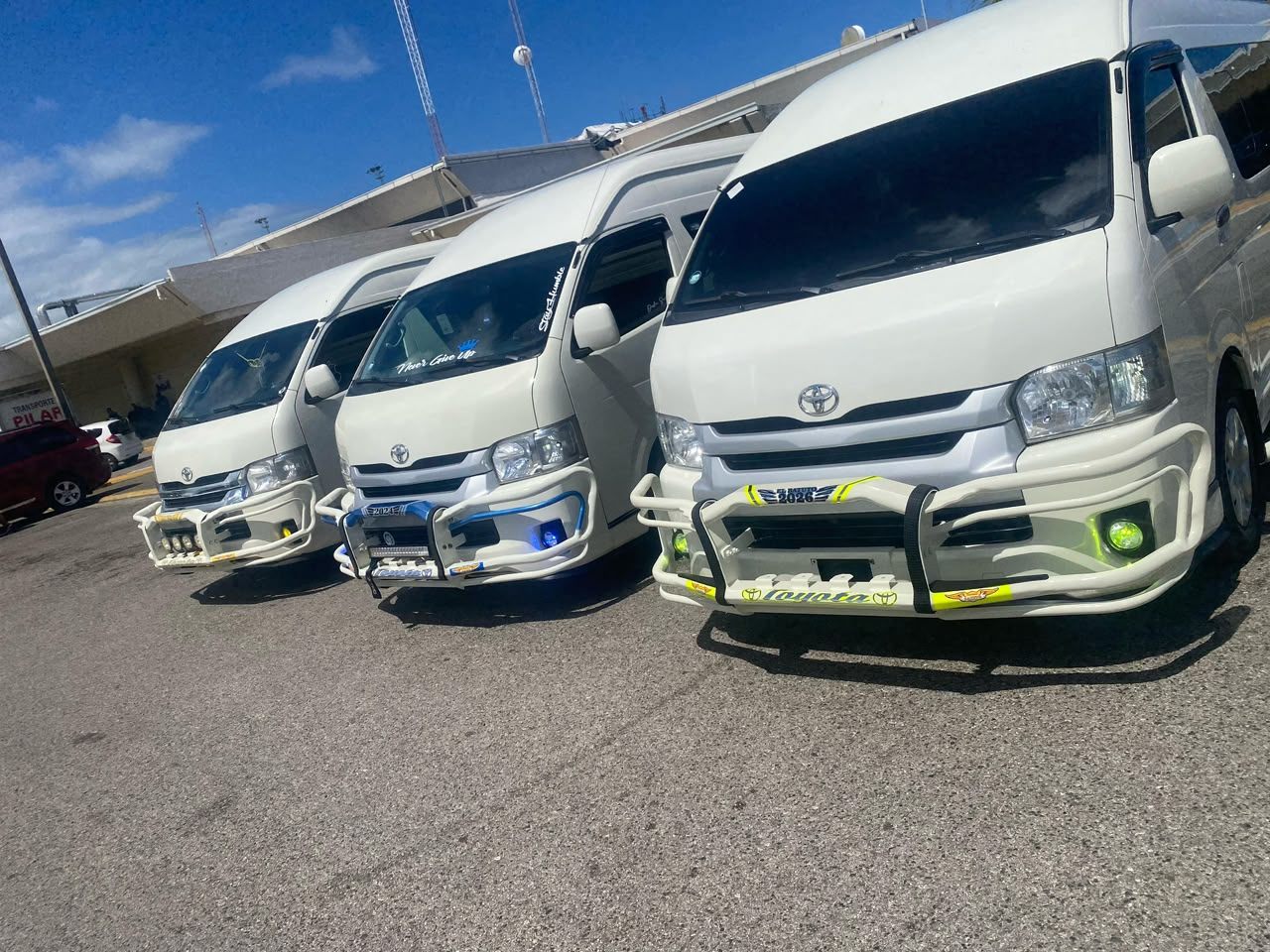Three white Toyota Hiace vans of the SG Caribbean fleet parked side by side