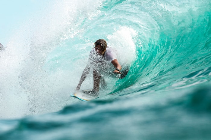 Surfer riding inside a turquoise barrel wave