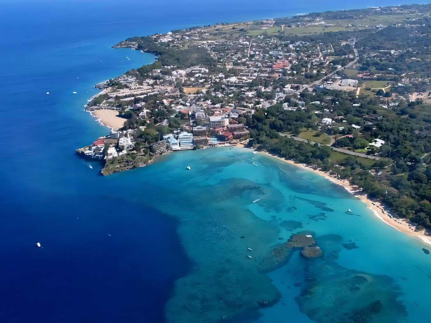 Aerial view of a turquoise Caribbean beach in the Dominican Republic with boats on clear water