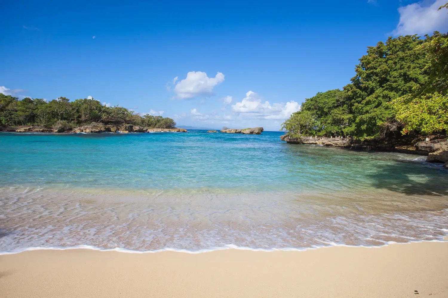 Calm turquoise cove backed by forested headlands on the coast at Río San Juan