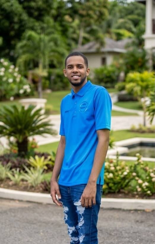 Leuris, one of our drivers, smiling in a garden wearing the company polo